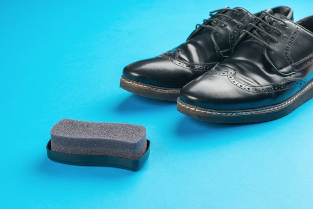 Éponge en mousse pour nettoyer les chaussures et les chaussures noires sur fond bleu