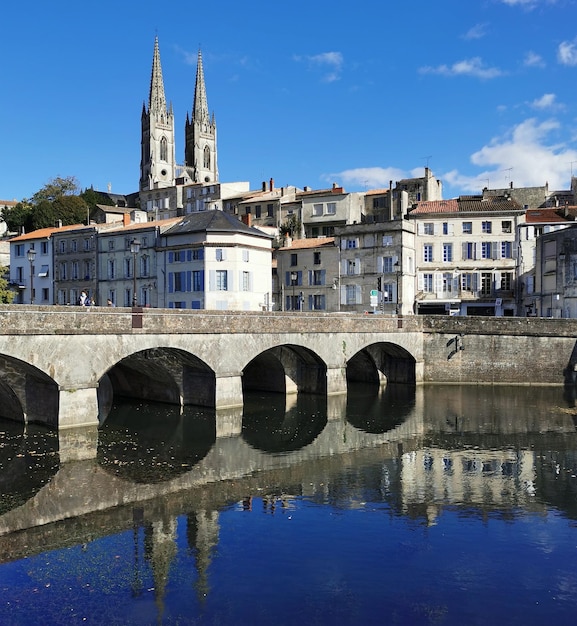 Photo pont d'arc sur la rivière par les bâtiments de la ville contre le ciel bleu