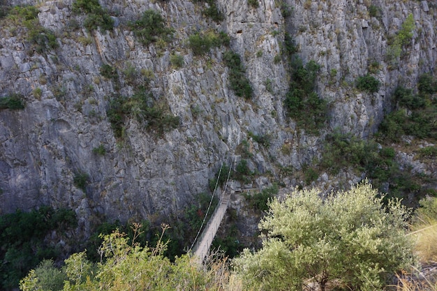 Un pont de bois est suspendu au-dessus d'une falaise.