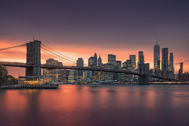Le pont de Brooklyn sur la rivière avec des bâtiments en arrière-plan au coucher du soleil