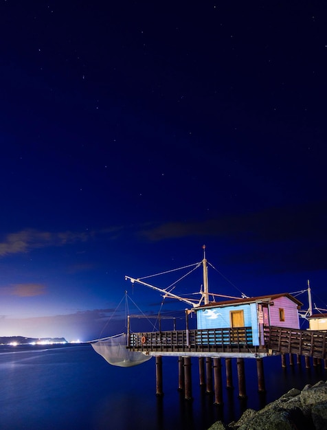 Photo pont éclairé sur la mer contre le ciel la nuit