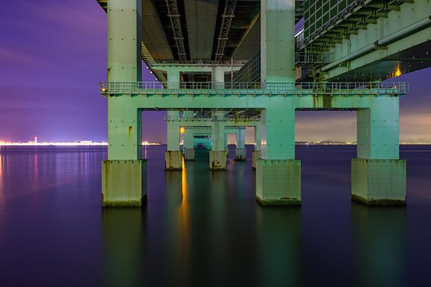 Photo pont éclairé sur la rivière contre le ciel la nuit