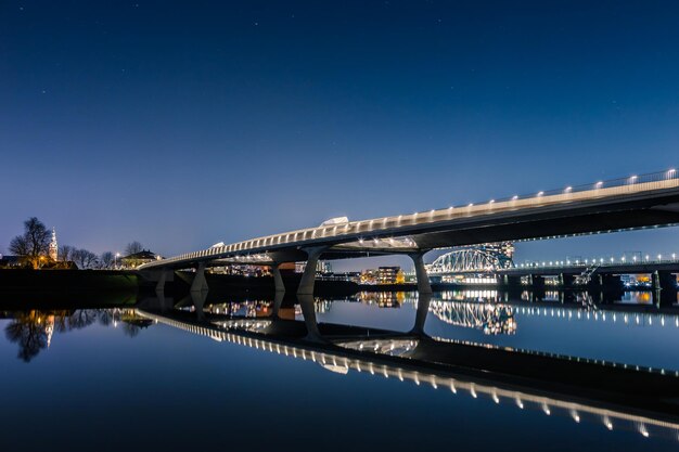 Photo pont éclairé sur la rivière contre le ciel la nuit