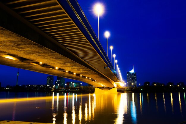 Photo pont éclairé sur la rivière contre le ciel la nuit