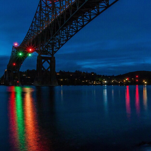 Photo pont éclairé sur la rivière la nuit