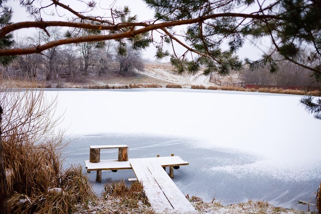 Un pont sur un lac gelé en hiver Il y a beaucoup d'arbres de Noël avec du givre autour