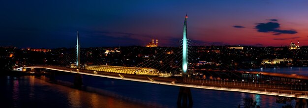 Photo pont de métro golden horn illuminé la nuit à istanbul, turquie