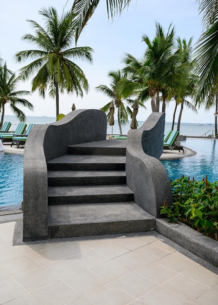 Pont noir avec escalier au-dessus de la piscine dans le jardin de palmiers