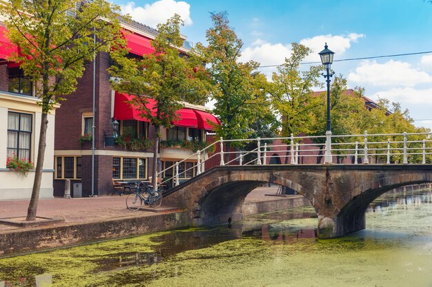 Le pont pittoresque avec une lanterne à travers le canal et des maisons typiques lors d'une journée ensoleillée à Delft, Hollande méridionale, Pays-Bas.