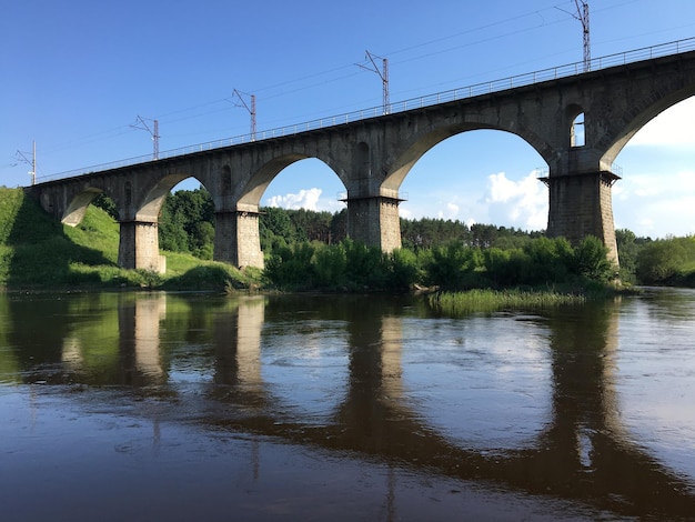 Un pont sur une rivière avec un ciel bleu et des arbres en arrière-plan