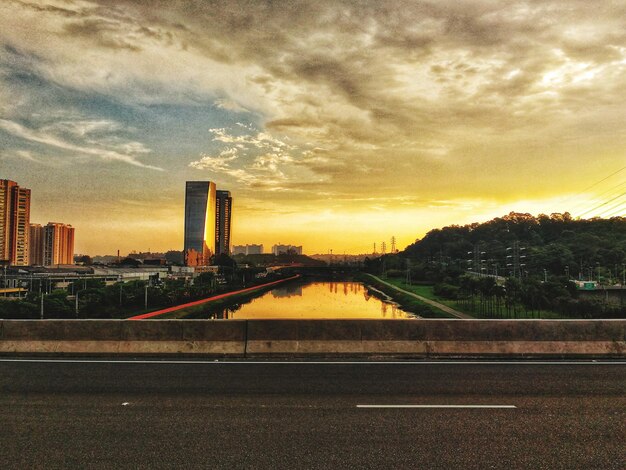 Pont sur la rivière par des bâtiments contre le ciel au coucher du soleil