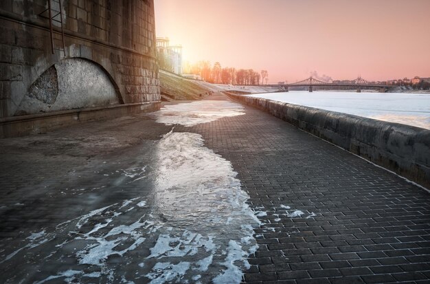 Pont Starovolzhsky sous le ciel rose au coucher du soleil et le remblai couvert de glace à Tver