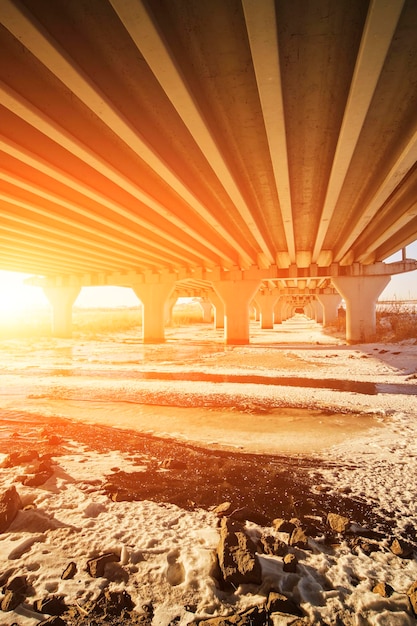 Pont de transport à moteur de colonnes arrière-plan coucher de soleil et une rivière gelée sous le pont