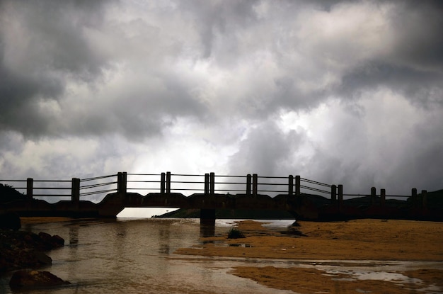 Pont de village éloigné et eau qui coule sous le pont dans un ciel nuageux. Sur le point de pleuvoir dans le village