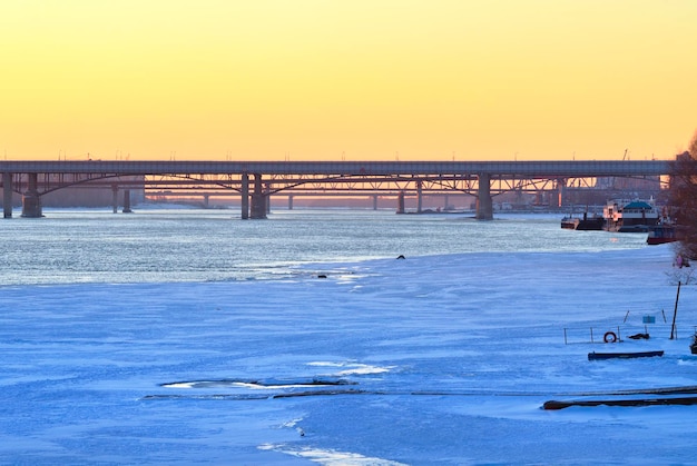 Ponts sur une rivière gelée La rive glacée de la grande rivière le soir au coucher du soleil Novosibirsk