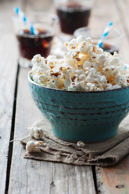 Pop-corn dans un bol et soda sur table en bois