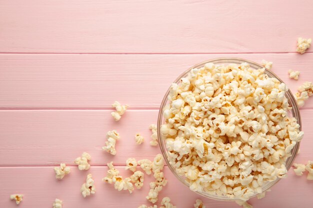 Pop-corn dans un bol en verre sur fond rose. Vue de dessus.