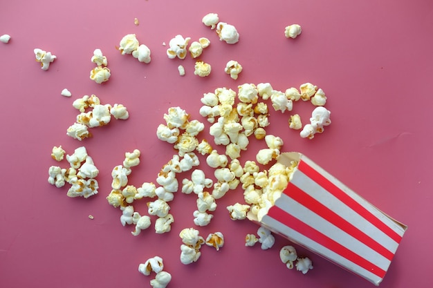 Pop-corn déversant d'un récipient sur fond rouge