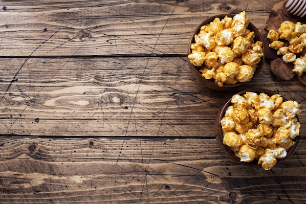 Pop-corn en glaçage au caramel dans des assiettes en bois sur une table rustique.