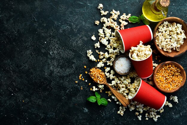 Pop-corn salé dans des gobelets en papier sur fond de pierre noire Vue de dessus