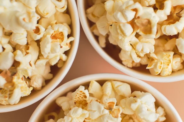 Pop-corn salé dans des gobelets en papier sur une surface beige