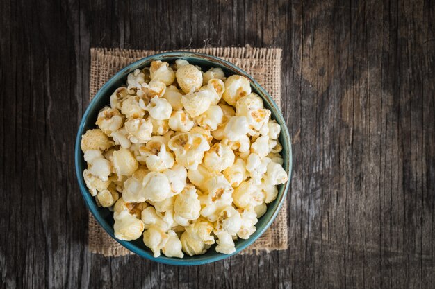 popcorn dans une vue de dessus de bol bleu sur un fond en bois foncé