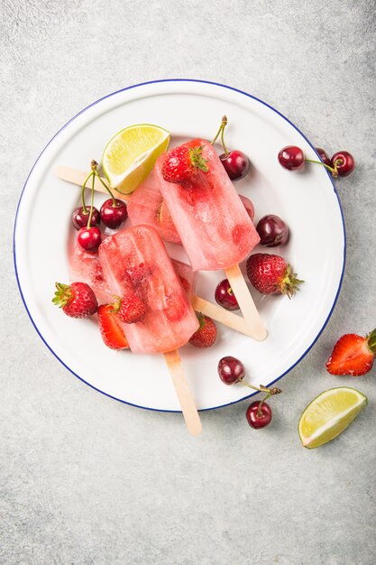 Popsicle Berry avec des bâtons en bois sur le comptoir en béton. Barres de fruits surgelées aux fraises maison