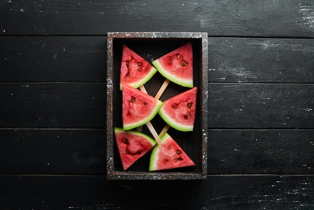 Popsicle pastèque sur fond noir Tranches de pastèque sur bâtons Vue de dessus Espace de copie gratuit