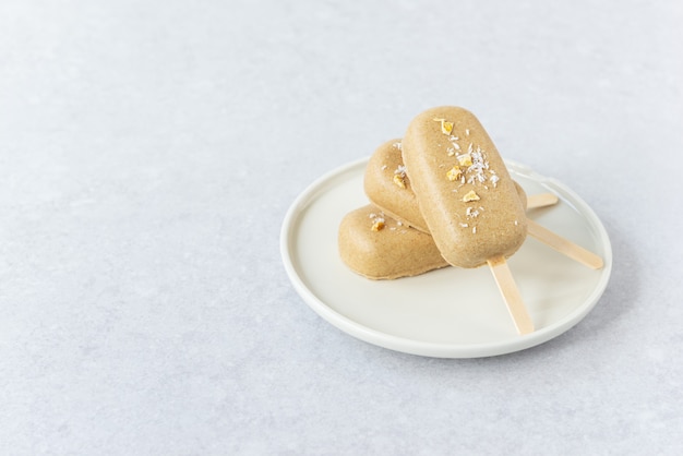 Popsicle végétalien avec noix de cajou au chocolat et morceaux de mangue sur une assiette