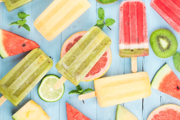 Popsicles de fruits entiers sains avec cantaloup de melon d'eau kiwi baies sur table vintage en bois