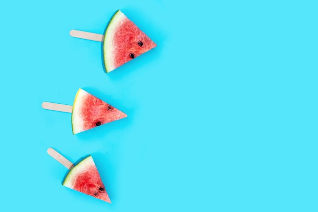 Popsicles de tranche de pastèque sur fond bleu.