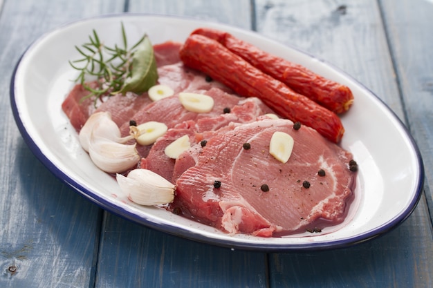 Porc aux saucisses fumées et ail sur plat en bois bleu