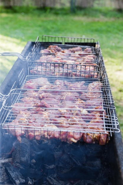 Porc cru assaisonné sur le gril Griller le shashlik à l'extérieur sur un barbecue Fête de grillades en plein air en été Soirée d'été ensoleillée Photo verticale