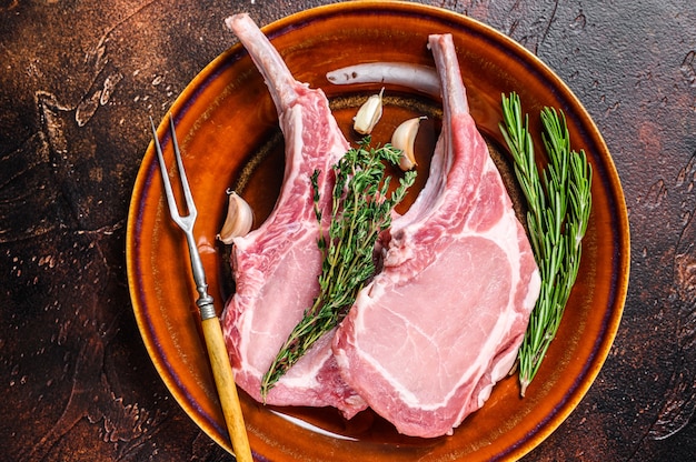 Le porc cru hache les steaks de viande avec du poivre et du sel. Fond sombre. Vue de dessus.