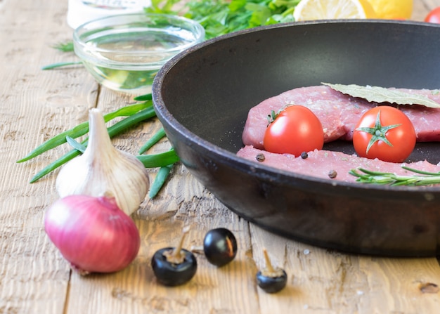 Porc cru sur une poêle à frire sur une table rustique.