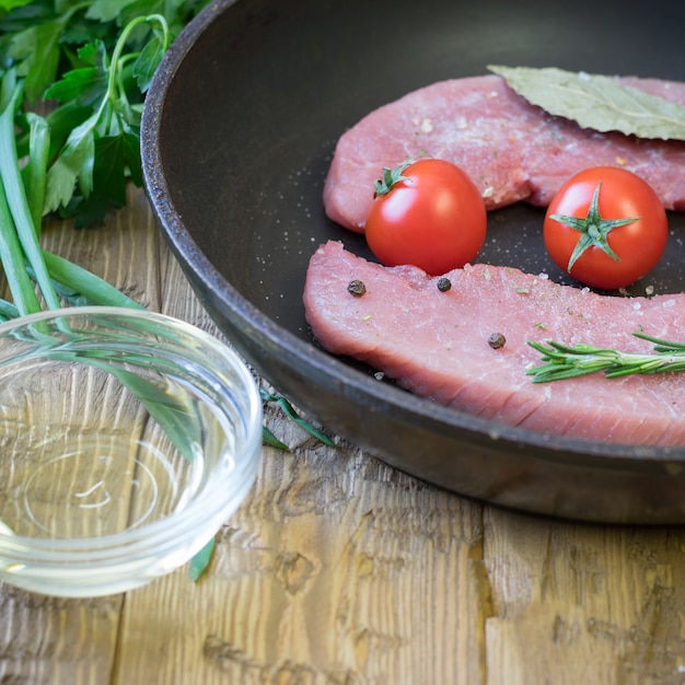 Porc cru sur une poêle à frire sur une table rustique.