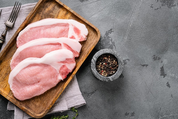 Porc frais avec des ingrédients pour la cuisine, sur fond de table en pierre grise, vue de dessus à plat, avec espace de copie pour le texte