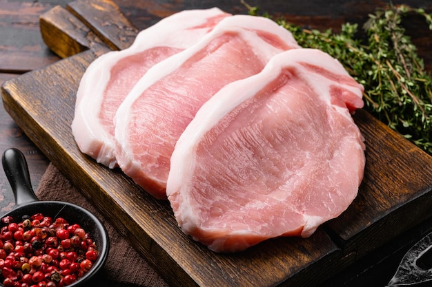 Photo porc frais avec des ingrédients pour la cuisine, sur le vieux fond de table en bois foncé
