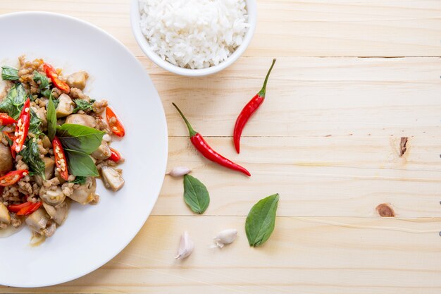 Porc salé aux feuilles de piment et de basilic et riz en plaque sur la table, vue de dessus