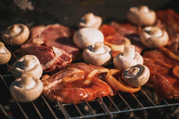 Porc à la sauce tomate avec rondelles d'oignon et champignons cuisinant à l'extérieur sur le gril barbecue extérieur