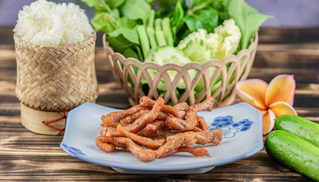 Porc séché au soleil frit et riz collant sur fond de table en bois.