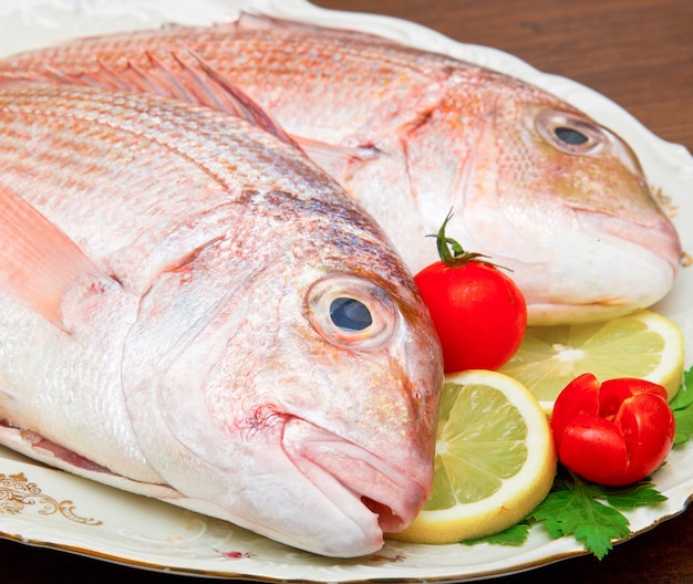 Porgy cru sur plat blanc sur table en bois