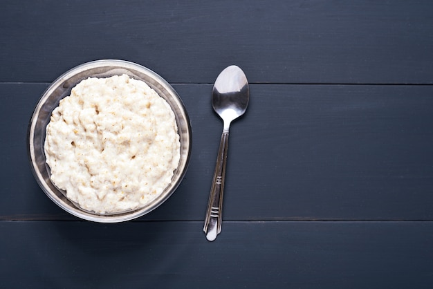 Porridge dans un bol en verre avec cuillère sur bois foncé avec copie espace, vue du dessus