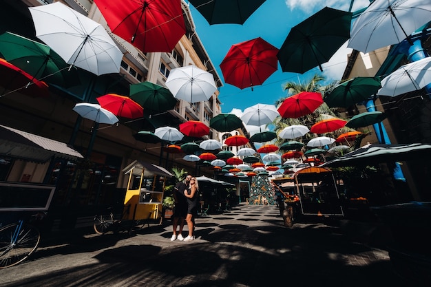 Port Louis, Maurice, un couple vêtu de noir se dresse sur une ruelle couverte de parapluies menant à la capitale