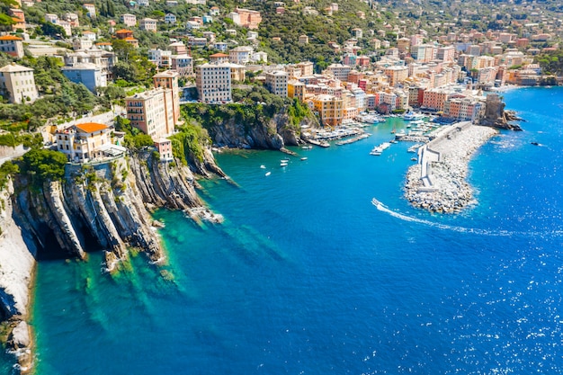 Port de plaisance et brise-lames où se trouve le phare. Bateau naviguant vers le port de la mer Ligure, Camogli près de Portofino, Italie. Vue aérienne sur les maisons colorées italiennes traditionnelles