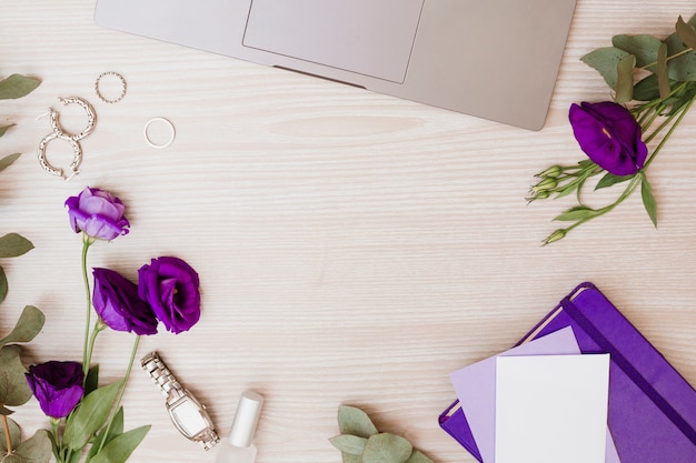 Portable; des boucles d'oreilles; anneaux de mariage; montre-bracelet; vernis à ongle; enveloppe; fleurs d'eustoma et agenda sur fond en bois