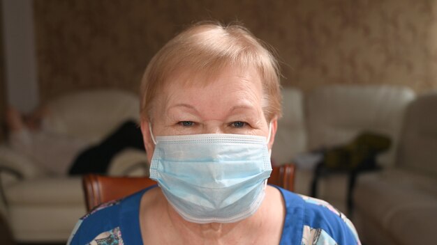 Portarait de femme âgée dans un masque de protection du visage, gros plan. La vie pendant une pandémie et la quarantaine