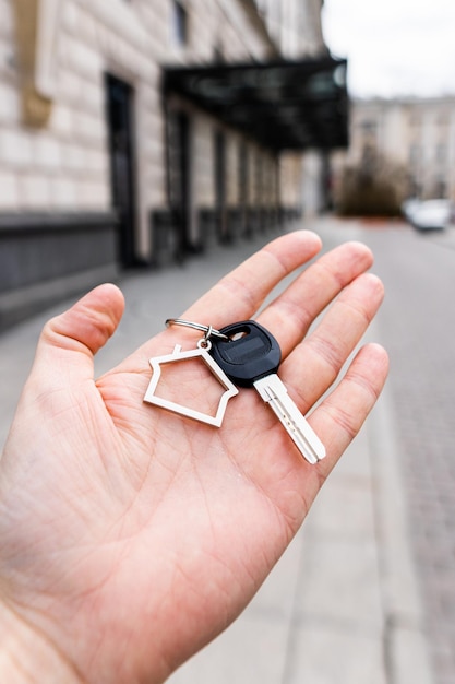 Porte-clés en forme de maison avec une clé dans la main de la personne