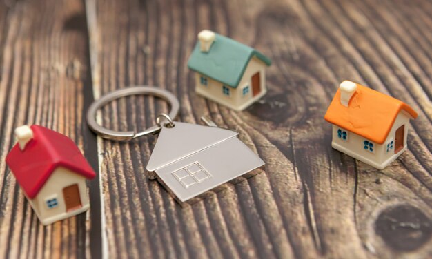 Porte-clés et maisons de jouets sur un fond en bois.