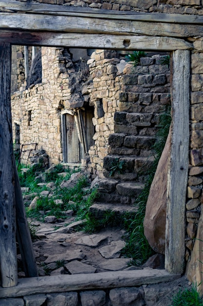 Porte dans le vieux village abandonné de Gamsutl à travers lequel une rue avec des ruines de maisons est visible